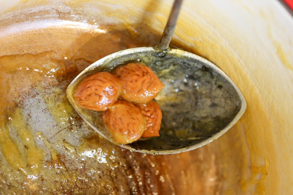 an antique ladle full of peach stones