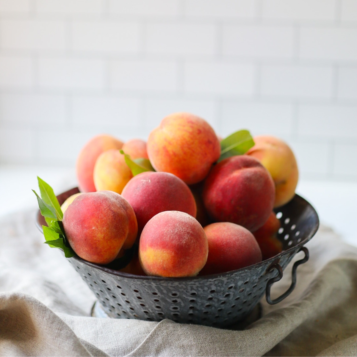 an antique colander full of peaches