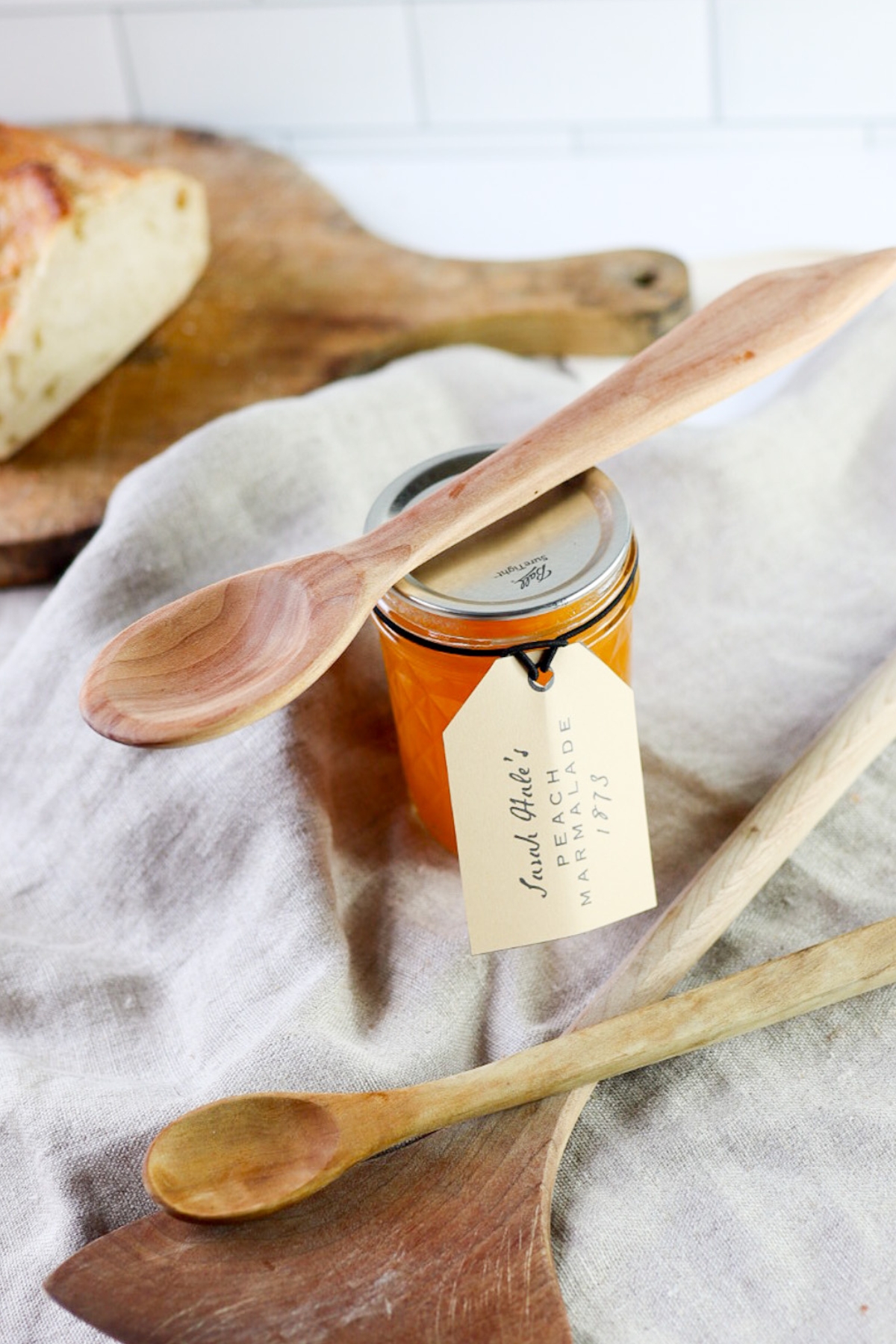 a jar of peach marmalade with bread and wooden spoons