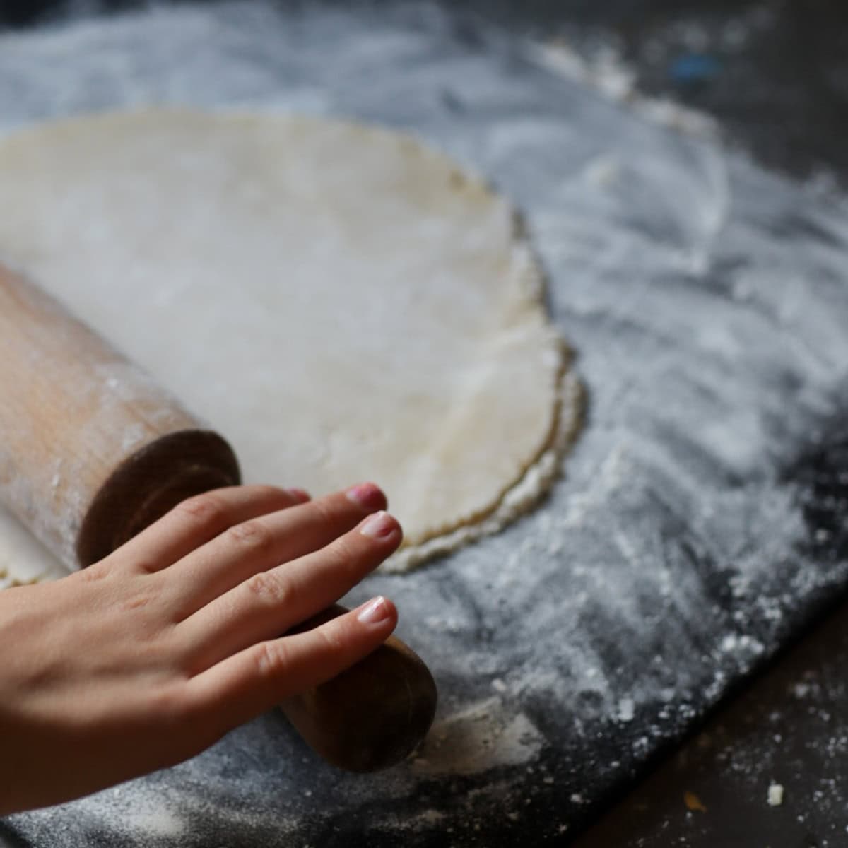a child's hands rolling out pie crust