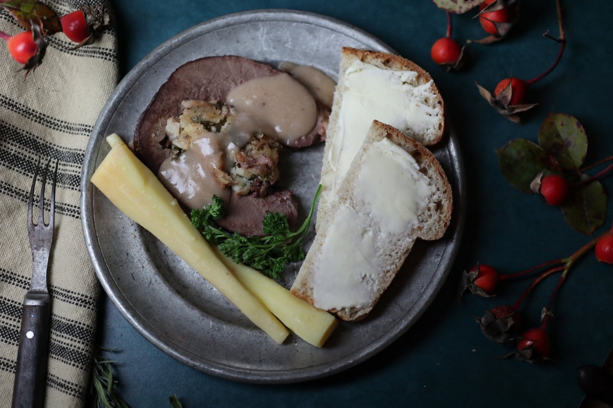 a slice of beef heart and stuffing with gravy on a pewter plate