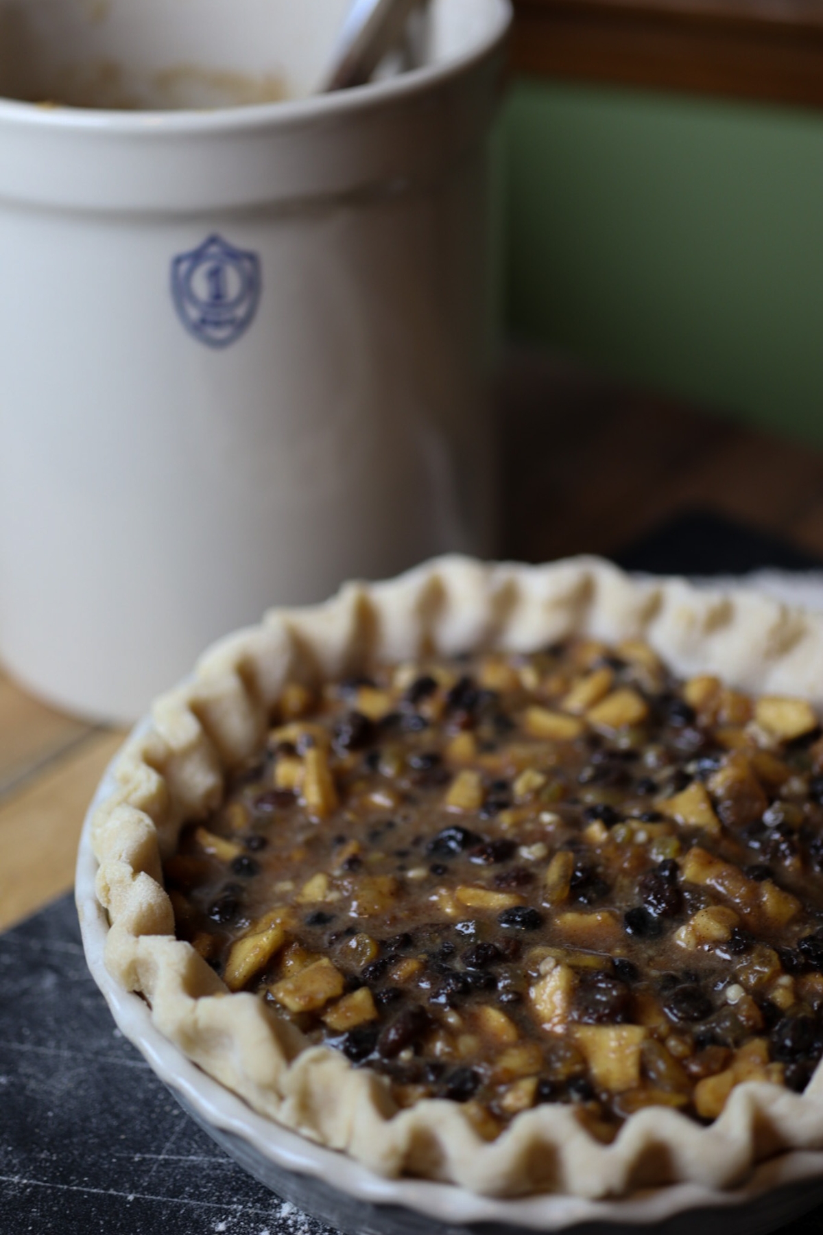 a mince pie in front of a crock full of 1800's mincemeat